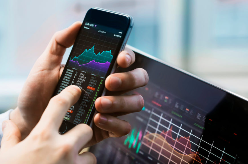 A stock trader trading using a phone and the best stock tips.