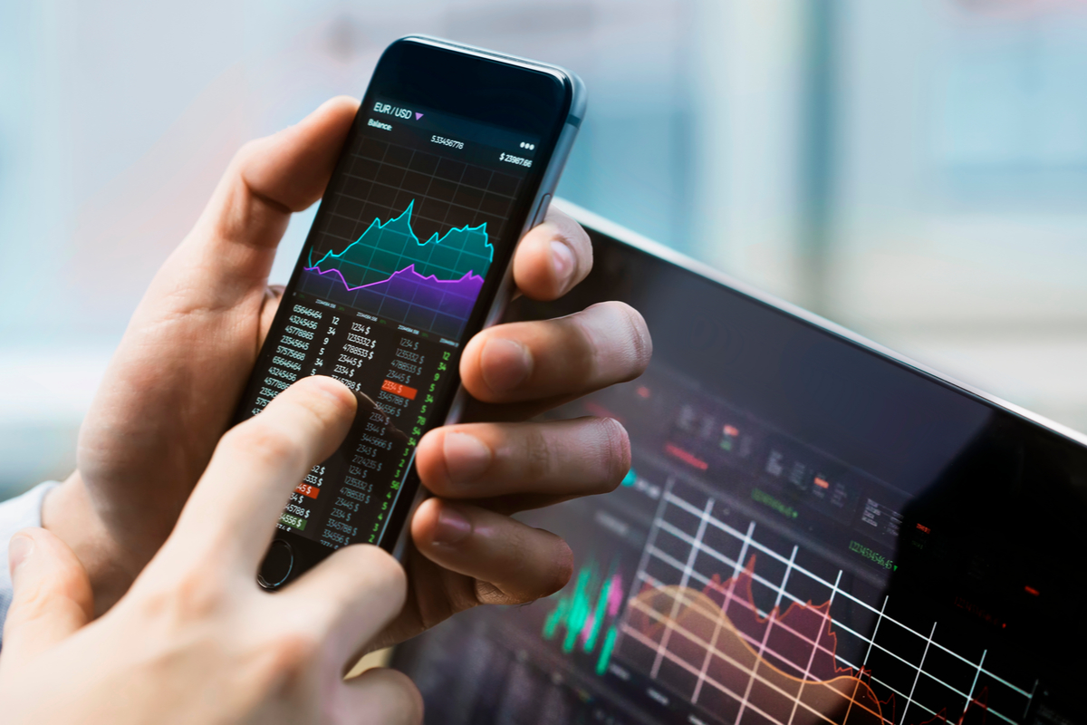 A stock trader trading using a phone and the best stock tips.